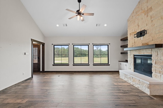 unfurnished living room featuring high vaulted ceiling, a stone fireplace, a wealth of natural light, and ceiling fan