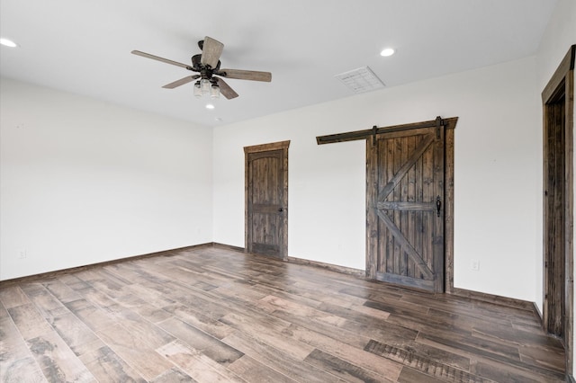 spare room featuring hardwood / wood-style floors, ceiling fan, and a barn door