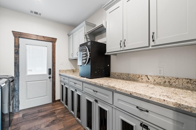 kitchen featuring washer and dryer, dark hardwood / wood-style floors, white cabinetry, and light stone countertops