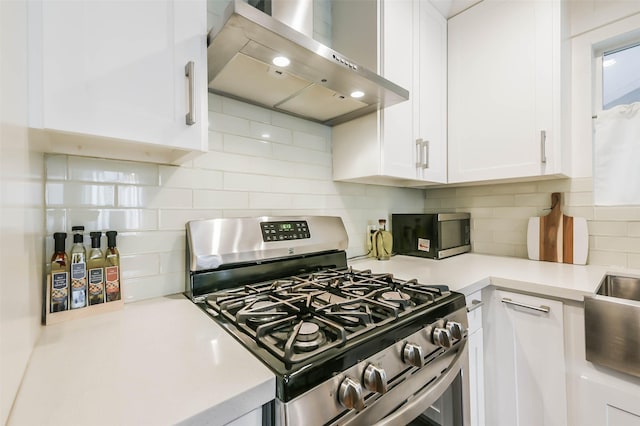 kitchen with white cabinets, wall chimney exhaust hood, backsplash, and stainless steel range with gas stovetop