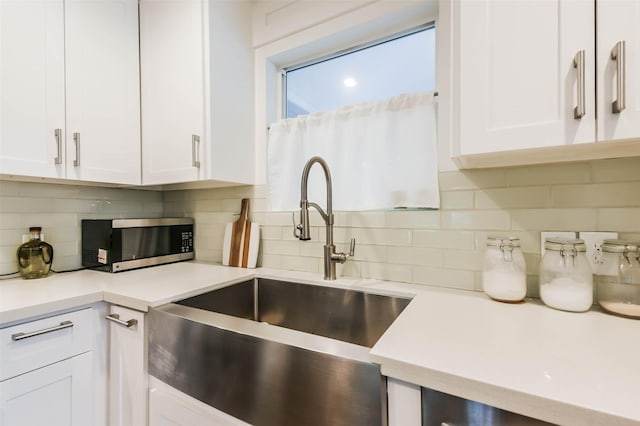 kitchen featuring decorative backsplash, white cabinetry, and sink