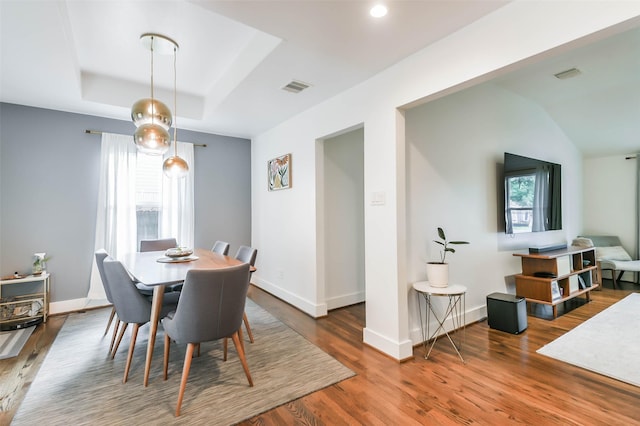 dining room with dark wood-type flooring and a tray ceiling