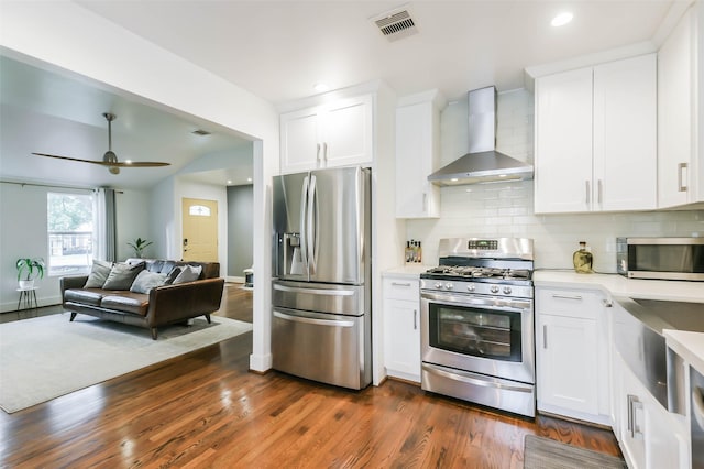 kitchen with white cabinets, appliances with stainless steel finishes, dark hardwood / wood-style floors, and wall chimney range hood