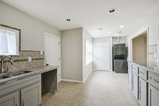 kitchen with light tile patterned flooring, sink, gray cabinetry, backsplash, and light stone countertops