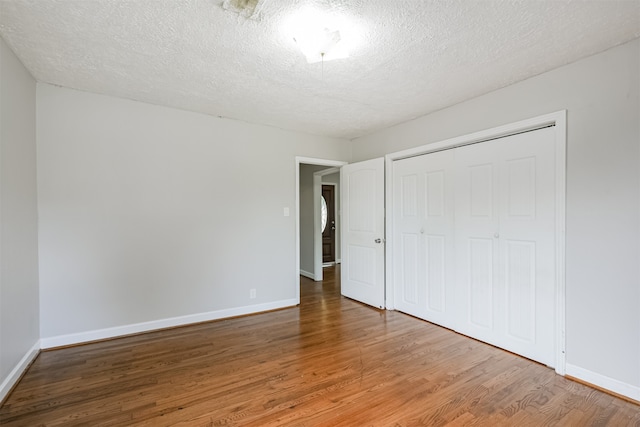 unfurnished bedroom featuring hardwood / wood-style flooring, a closet, and a textured ceiling