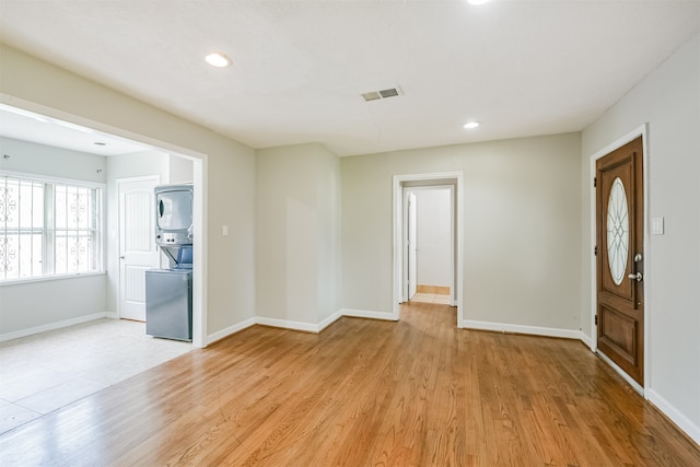 interior space with light hardwood / wood-style flooring and stacked washer / drying machine