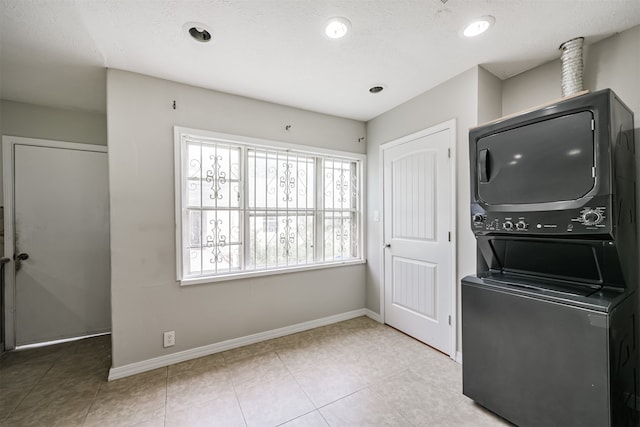 clothes washing area with stacked washer / dryer and light tile patterned floors