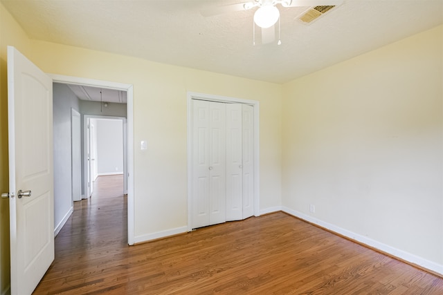 unfurnished bedroom with ceiling fan, a closet, and wood-type flooring