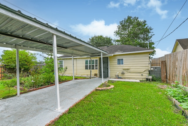 rear view of property with a lawn and a carport