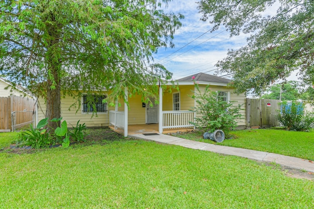 view of property hidden behind natural elements featuring a porch and a front yard