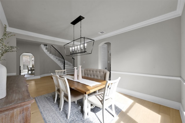 dining space featuring a chandelier, crown molding, and light hardwood / wood-style flooring