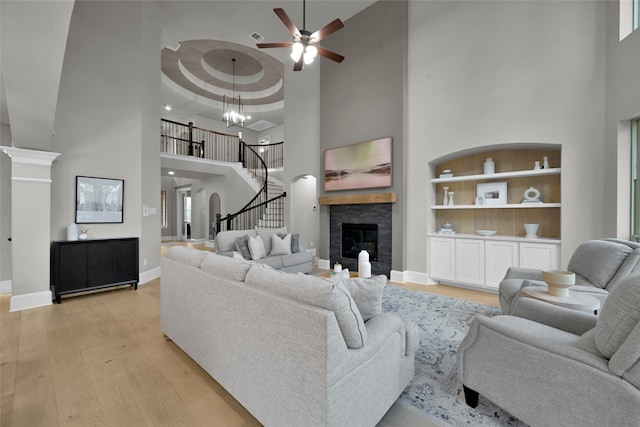 living room featuring a raised ceiling, a towering ceiling, ceiling fan with notable chandelier, and light hardwood / wood-style floors