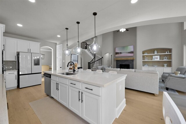 kitchen with a center island with sink, sink, white refrigerator, and white cabinetry