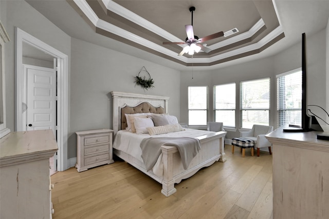 bedroom featuring a tray ceiling, ceiling fan, light hardwood / wood-style floors, and crown molding