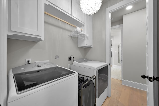 laundry room with washer and dryer, cabinets, a chandelier, and light hardwood / wood-style floors