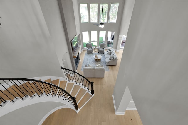 stairway with a high ceiling, ceiling fan, and hardwood / wood-style flooring