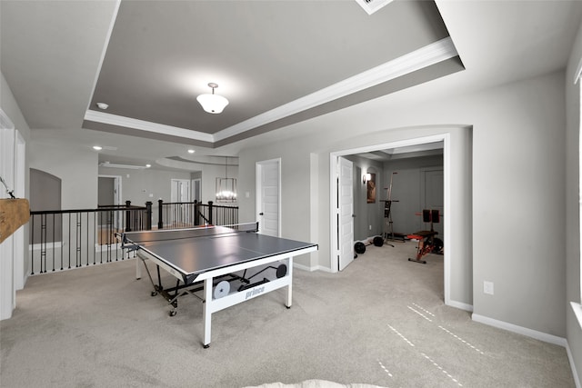 recreation room with crown molding, light carpet, and a tray ceiling