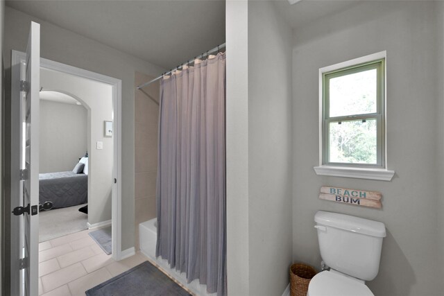 bathroom with shower / bath combo with shower curtain, tile patterned flooring, toilet, and plenty of natural light