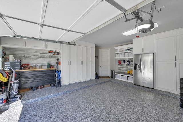 garage featuring a garage door opener and stainless steel refrigerator with ice dispenser