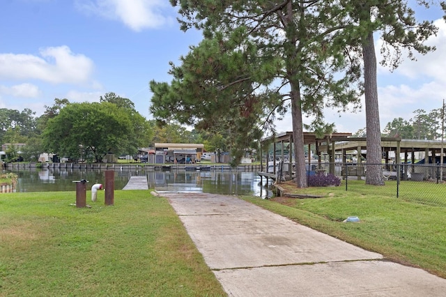 view of property's community with a lawn, a water view, and fence