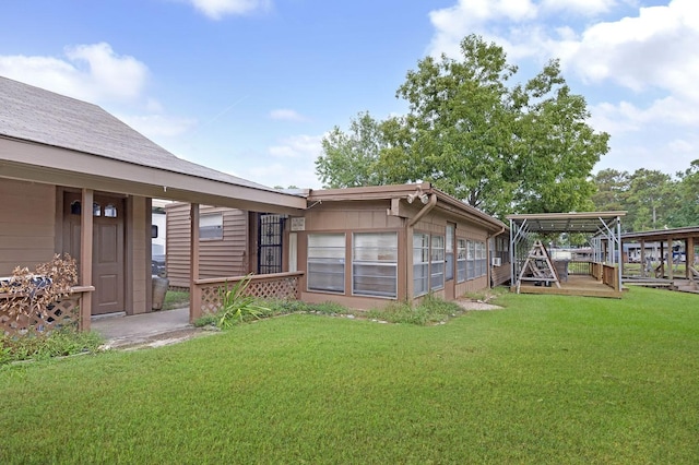 back of property with a carport, a lawn, and a wooden deck