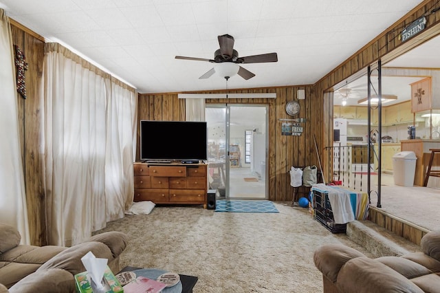 carpeted living area with a ceiling fan and wood walls