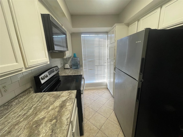 kitchen with light tile patterned flooring, stainless steel range with electric cooktop, refrigerator, white cabinets, and backsplash