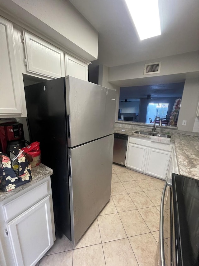 kitchen featuring sink, light tile patterned floors, kitchen peninsula, stainless steel appliances, and white cabinets