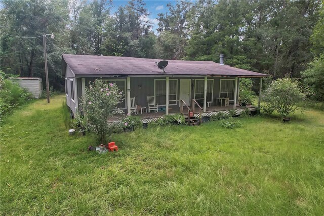 rear view of property featuring a yard and a storage shed