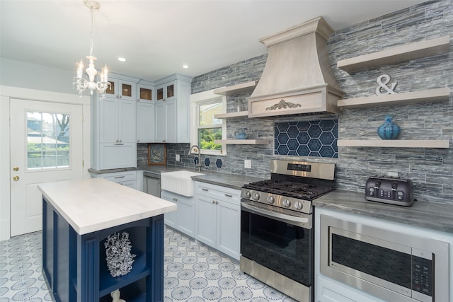 kitchen featuring custom exhaust hood, white cabinets, hanging light fixtures, sink, and stainless steel appliances