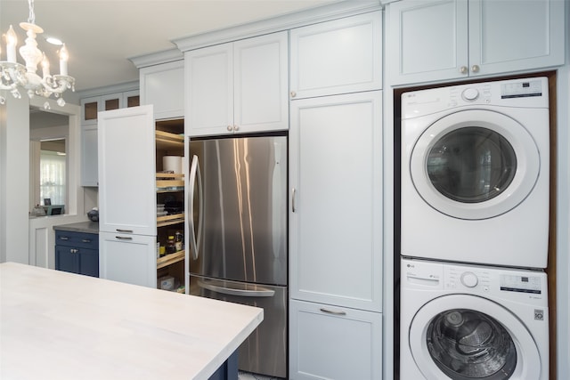 clothes washing area with a notable chandelier and stacked washer and dryer