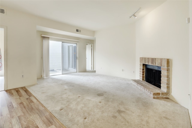 unfurnished living room featuring carpet floors, a fireplace, visible vents, and track lighting