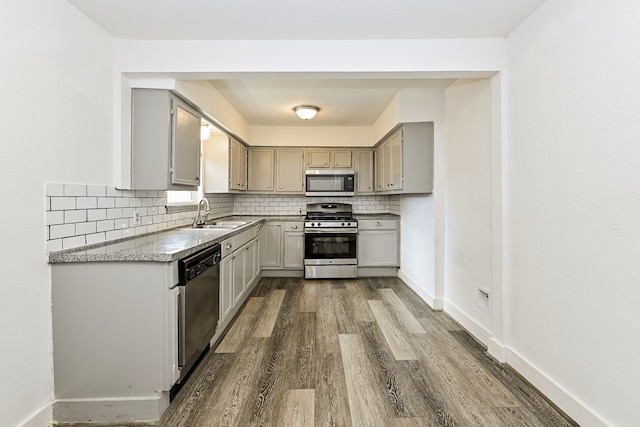 kitchen with tasteful backsplash, sink, dark hardwood / wood-style floors, appliances with stainless steel finishes, and gray cabinetry