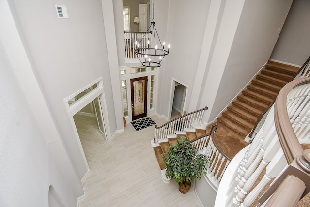 foyer featuring light tile patterned flooring, an inviting chandelier, and a high ceiling