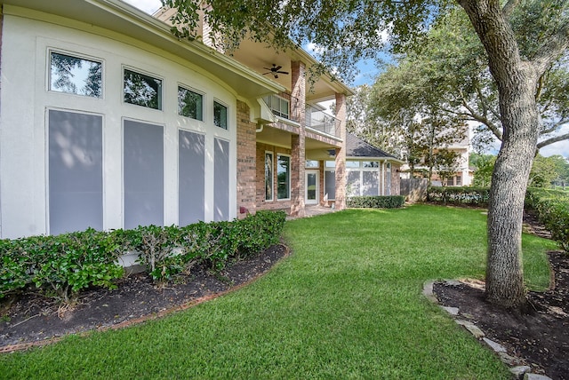 view of yard featuring a balcony and ceiling fan