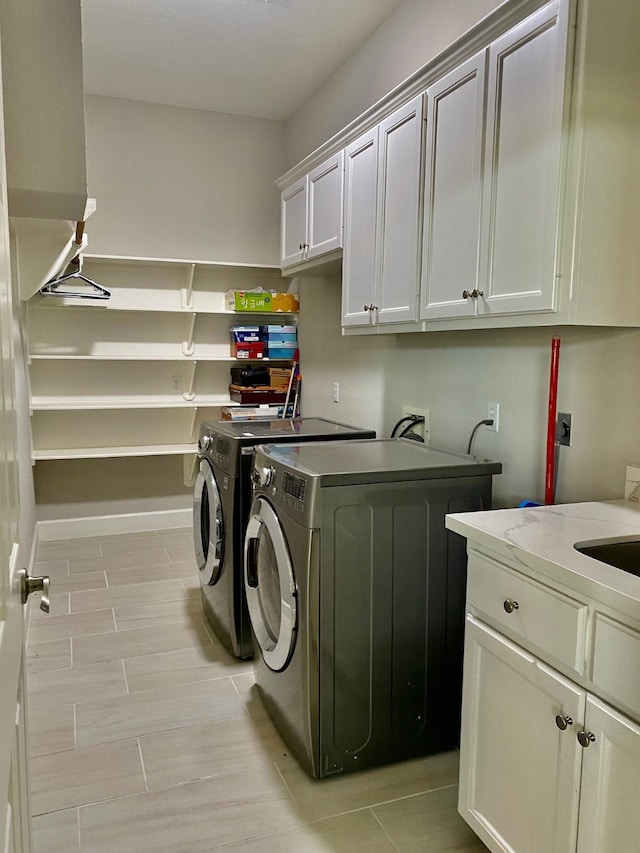 clothes washing area with cabinets and washing machine and dryer