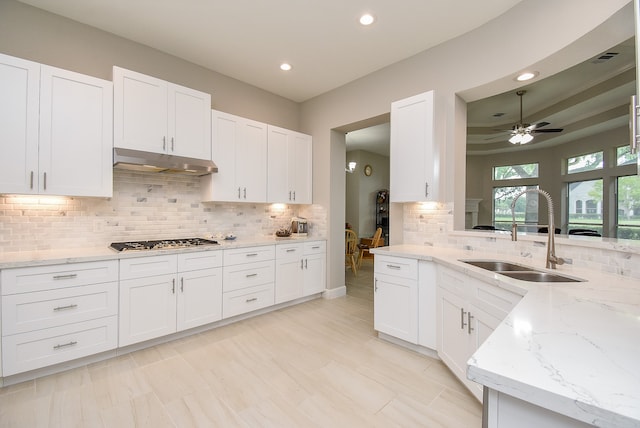 kitchen with stainless steel gas stovetop, tasteful backsplash, sink, ceiling fan, and white cabinets