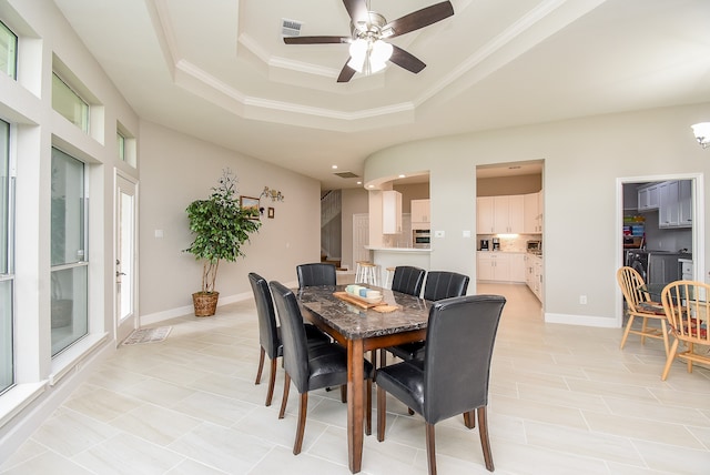 dining area featuring ceiling fan, plenty of natural light, a raised ceiling, and crown molding