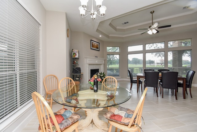 tiled dining space featuring a tray ceiling, ceiling fan with notable chandelier, and crown molding