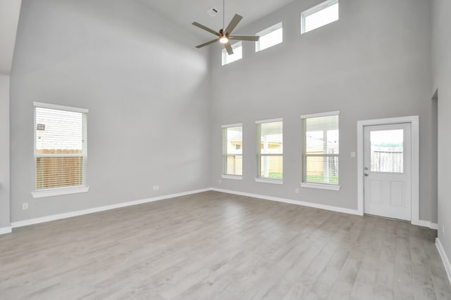 unfurnished living room featuring a high ceiling, light hardwood / wood-style flooring, and ceiling fan