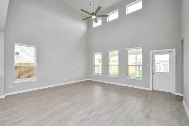 15327 Statice Trl, Houston, TX 77044 - unfurnished living room featuring a towering ceiling, healthy amount of natural light, a ceiling fan, wood finished floors, and baseboards