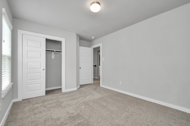 unfurnished bedroom featuring a closet, light carpet, and multiple windows