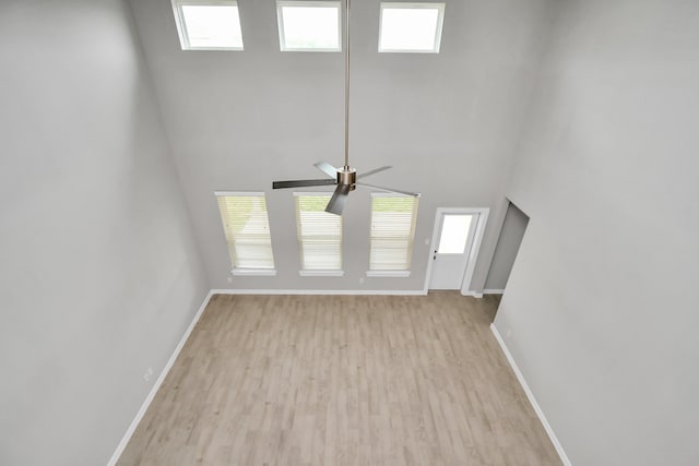 unfurnished living room with a high ceiling, light hardwood / wood-style flooring, and ceiling fan