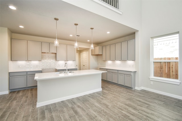 kitchen featuring gray cabinetry, light wood-type flooring, sink, and hanging light fixtures