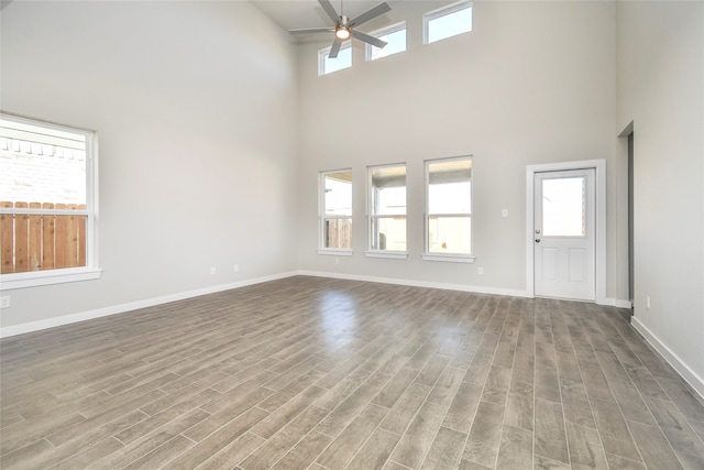 unfurnished living room featuring a high ceiling, light hardwood / wood-style flooring, and plenty of natural light