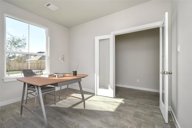 office featuring a healthy amount of sunlight, wood-type flooring, and french doors