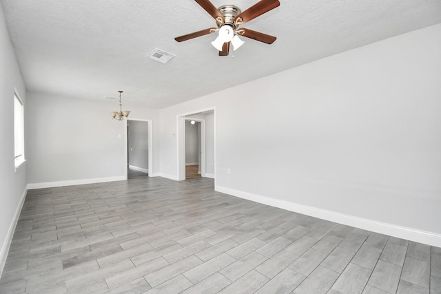 spare room with baseboards, visible vents, wood finished floors, a textured ceiling, and ceiling fan with notable chandelier