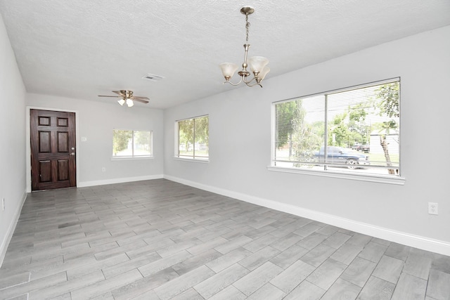 spare room featuring a textured ceiling, ceiling fan with notable chandelier, wood finished floors, visible vents, and baseboards