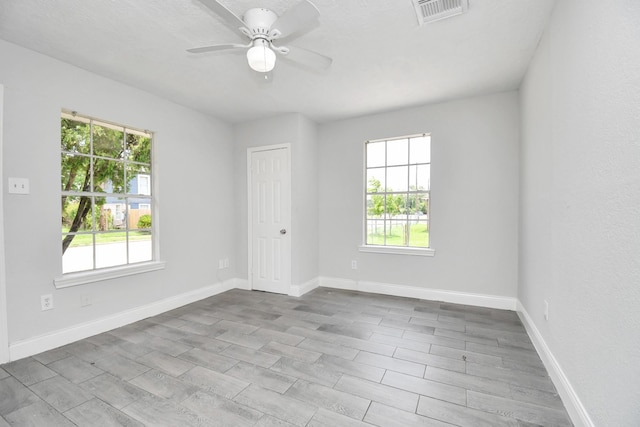 spare room with visible vents, plenty of natural light, baseboards, and ceiling fan