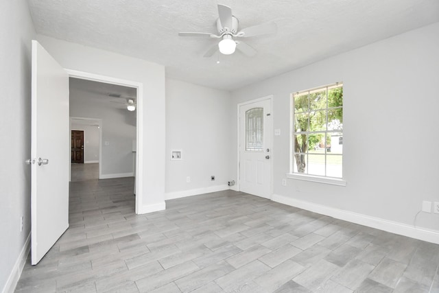 empty room featuring ceiling fan, a textured ceiling, and baseboards